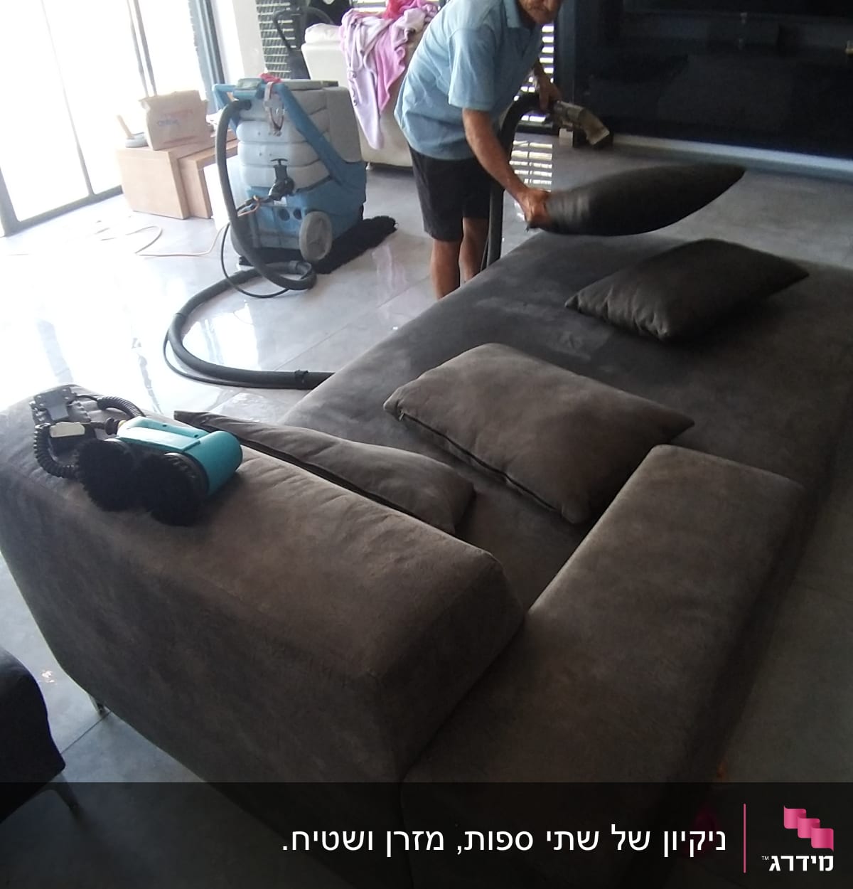 אדם מנקה ספה עם מכונת ניקוי מקצועית